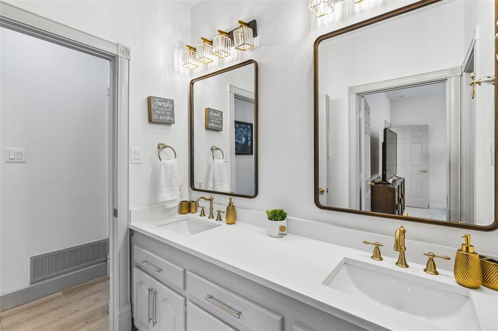 Dual vanity with integrated sinks and white countertops, complemented by gold-finish fixtures and framed mirrors