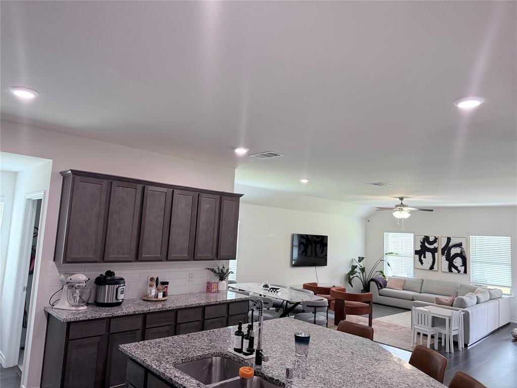 Kitchen featuring wood-finish cabinetry, granite countertops, and a tile backsplash Kitchen featuring wood-finish cabinetry, granite countertops, and a tile backsplash