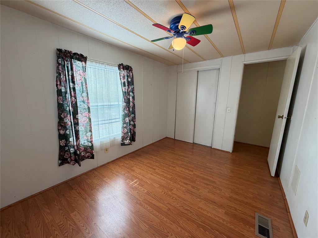 Wood-finish flooring, white walls, and a ceiling fan with integrated lighting