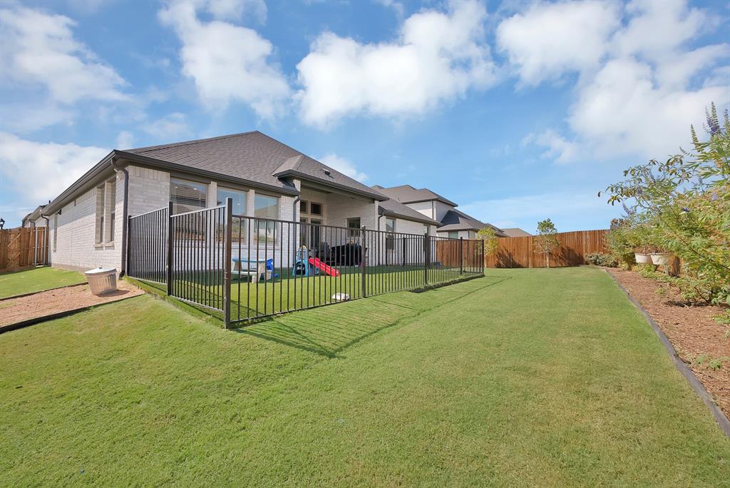 Another view of the backyard showcasing the wrought iron fenced in play area with artificial turf.