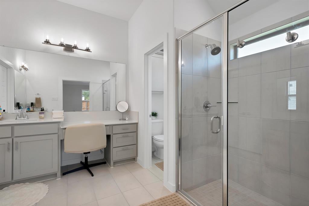 Glass-enclosed shower with tile surround and transom window.
