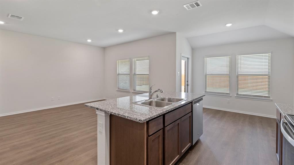 Kitchen island featuring a dual-basin stainless steel sink, granite-style countertop, and stainless steel dishwasher