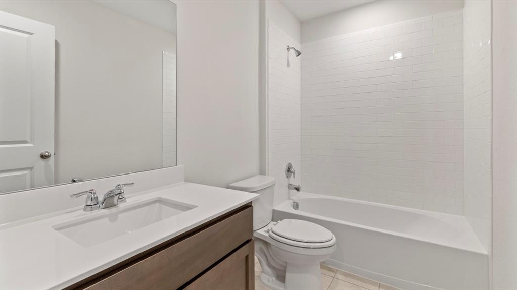Bathroom featuring a built-in vanity with an integrated sink, polished chrome fixtures, frameless mirror, and a tiled shower-tub combination