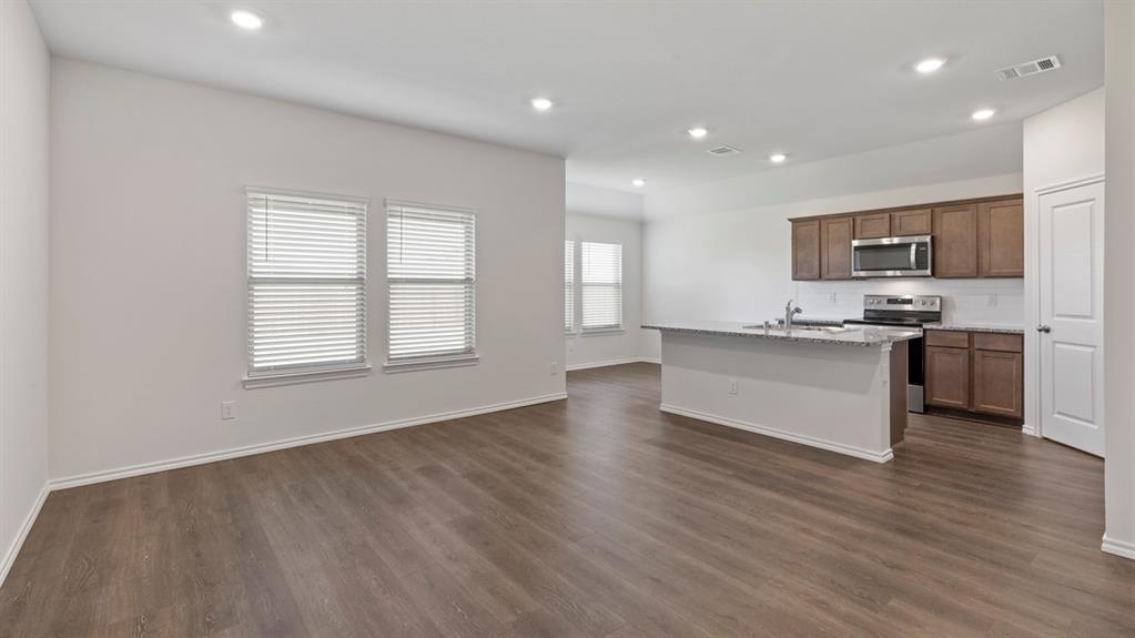 Open-concept living space featuring wood-finish flooring, recessed lighting, and ample natural light from multiple windows