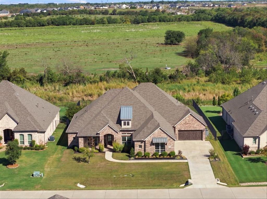Brick exterior with stone accents, covered entry, attached garage, concrete driveway, and manicured landscaping