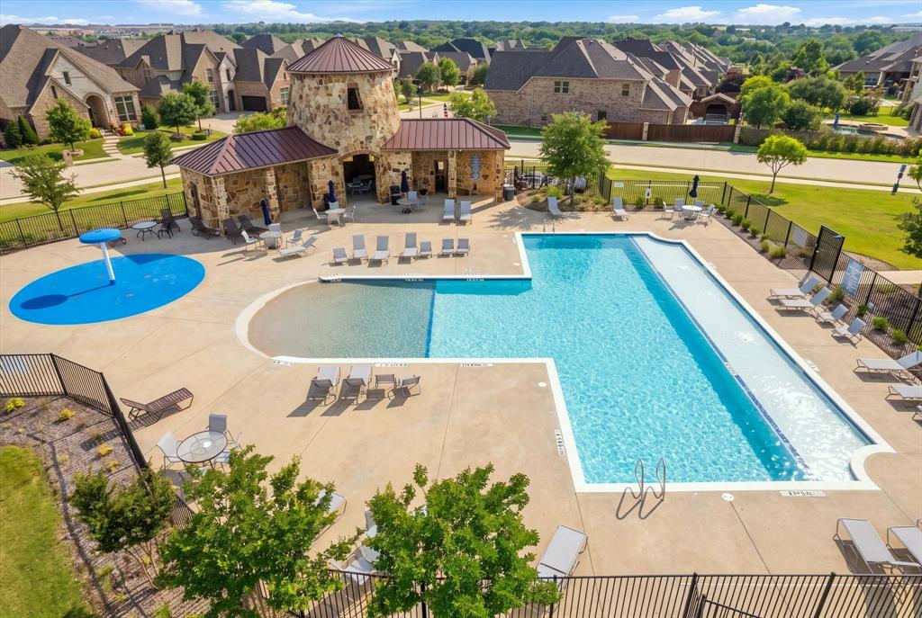 Expansive outdoor pool area featuring a large swimming pool, separate splash pad, and a stone-clad building with a covered patio