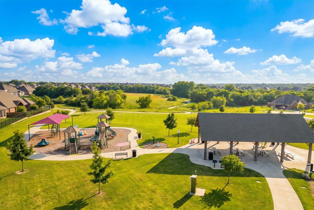 Expansive community greenspace featuring a playground, covered pavilion, walking paths, and mature trees