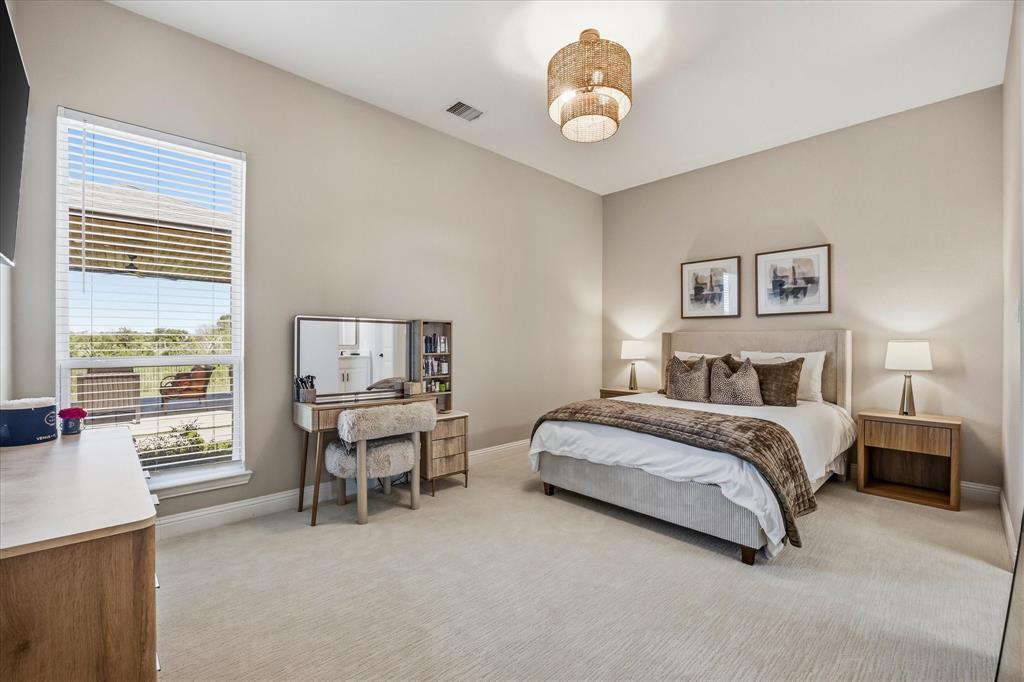 Expansive room with neutral carpeting, a large window, a fabric-upholstered bed frame, and a woven pendant light fixture