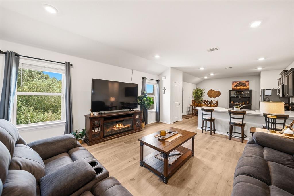 Open-concept living space featuring wood-finish flooring, recessed lighting, and a built-in electric fireplace