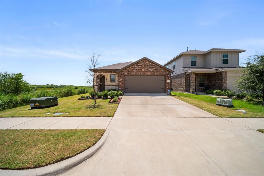Brick and stone exterior with an attached two-car garage, concrete driveway, and front lawn landscaping