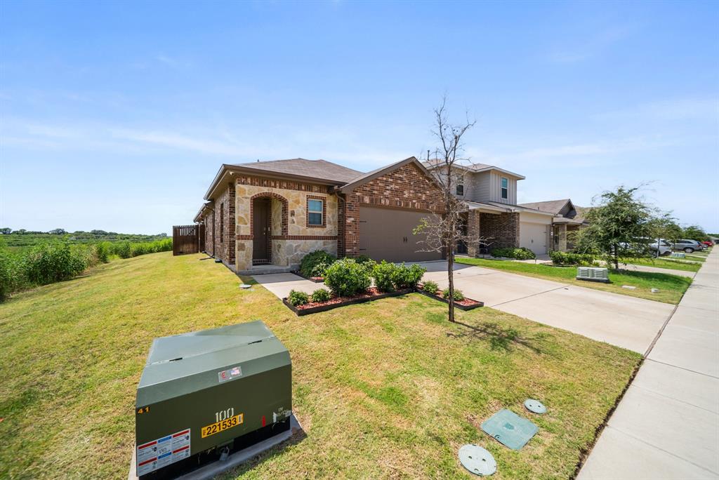 Brick and stone facade, attached garage, concrete driveway, front yard landscaping, and a side fence