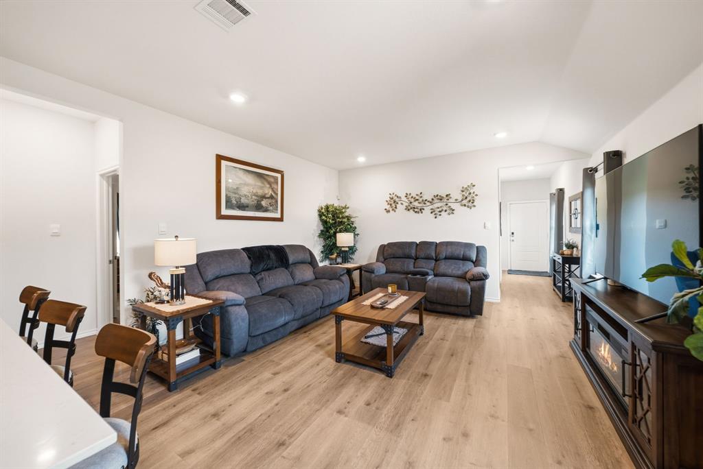 Open-concept living space featuring wood-finish flooring, recessed lighting, and a vaulted ceiling