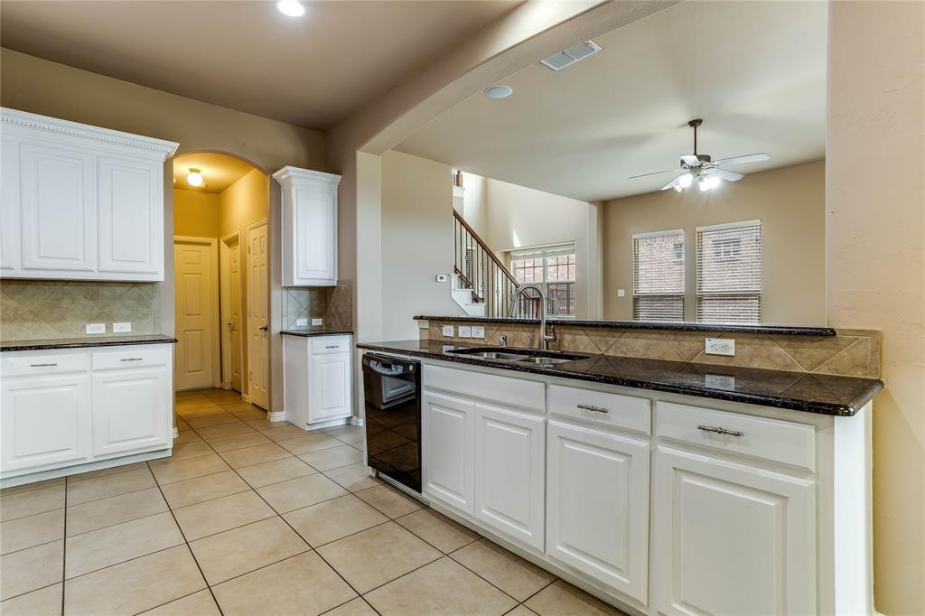 Kitchen featuring white cabinetry, dark countertops, a tile backsplash, and tile flooring
