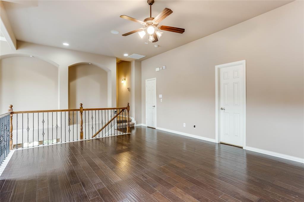 Expansive room featuring wood-finish flooring, a ceiling fan with integrated lighting, recessed lighting, and a wrought iron and wood railing
