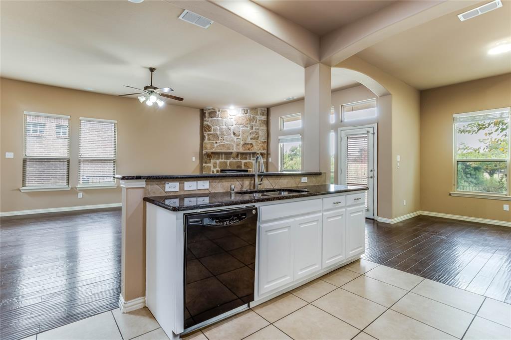 Kitchen island with dark countertop, integrated sink, and white cabinetry