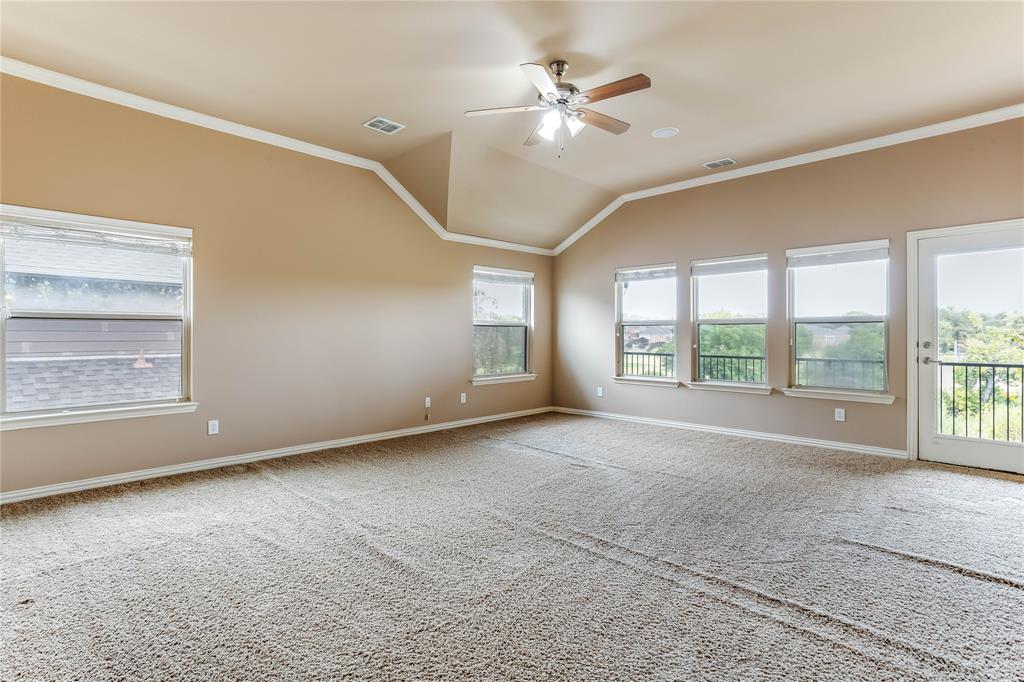 Vaulted ceiling with crown molding, ceiling fan, and multiple windows