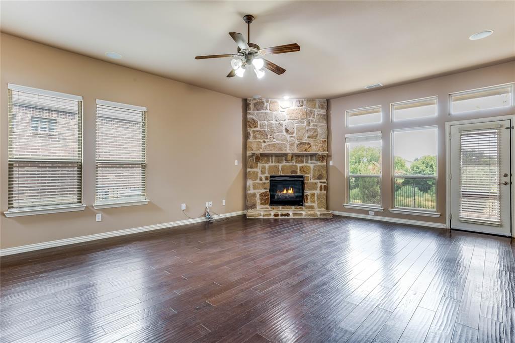 Expansive living area with wood-finish flooring, a stone fireplace, and multiple windows