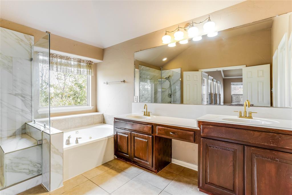 Built-in soaking tub, separate glass-enclosed shower with tile surround, dual vanity with undermount sinks, and wood-finish cabinetry