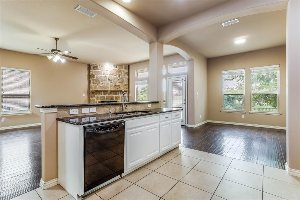 Open-concept kitchen featuring an island with a breakfast bar, white cabinetry, a black dishwasher, and dark stone-finish countertops