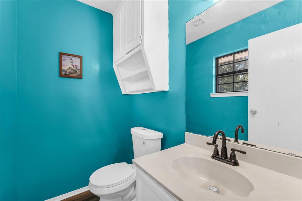 Bathroom featuring a single vanity with an integrated sink, dark bronze-finish faucet, and a wall-mounted mirror