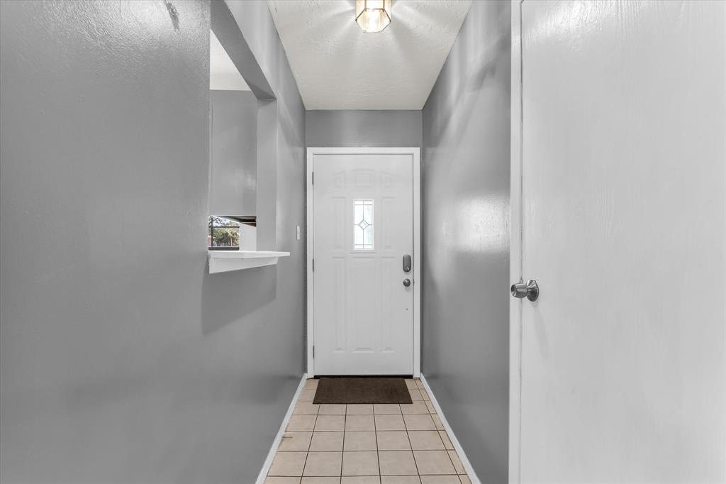 Entryway featuring a white door with decorative glass inserts, recessed lighting, and tile flooring