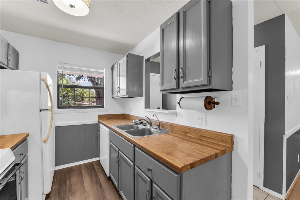 Kitchen featuring wood-finish countertops, grey cabinetry, stainless steel double-basin sink, and wood-finish flooring