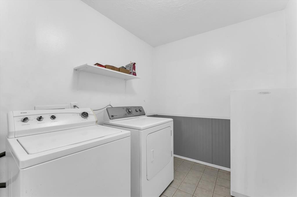 Laundry area featuring tile flooring, wainscoting, and an integrated shelf