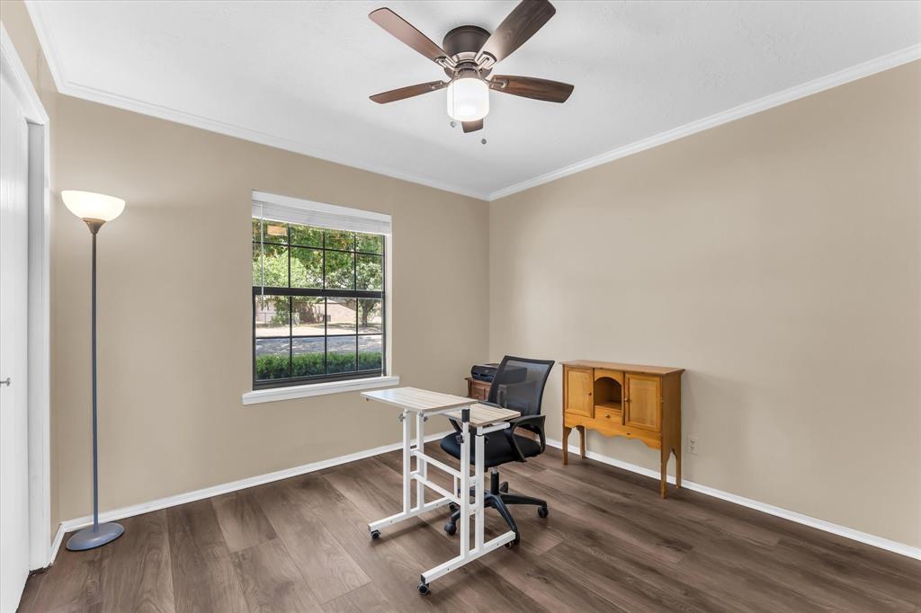 Wood-finish flooring, single window with white blinds, ceiling fan with integrated lighting, and crown molding