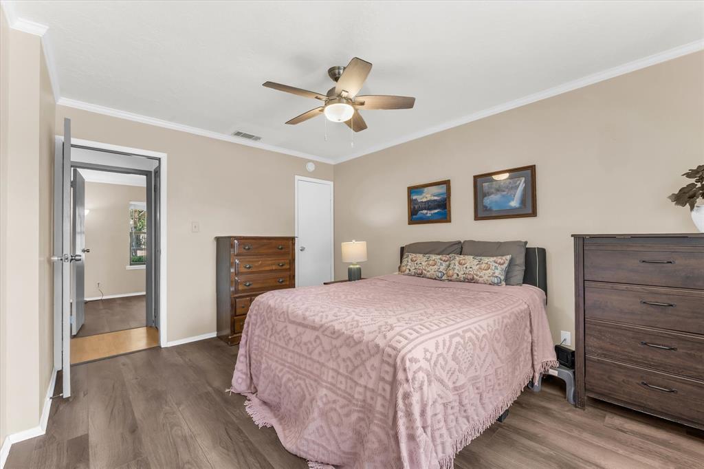 Wood-finish flooring throughout, complemented by crown molding and a ceiling fan