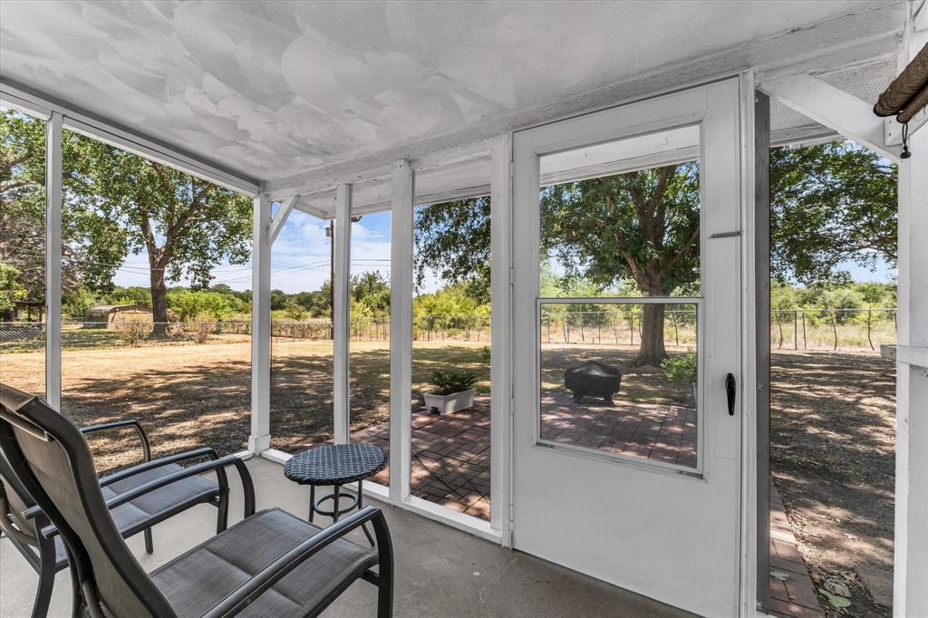 Screened porch with concrete flooring and a full-light door