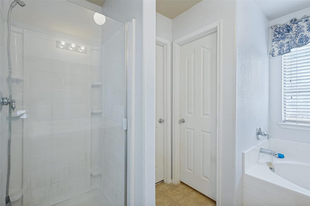 Shower enclosure with clear glass door, tile surround, and built-in shelving
