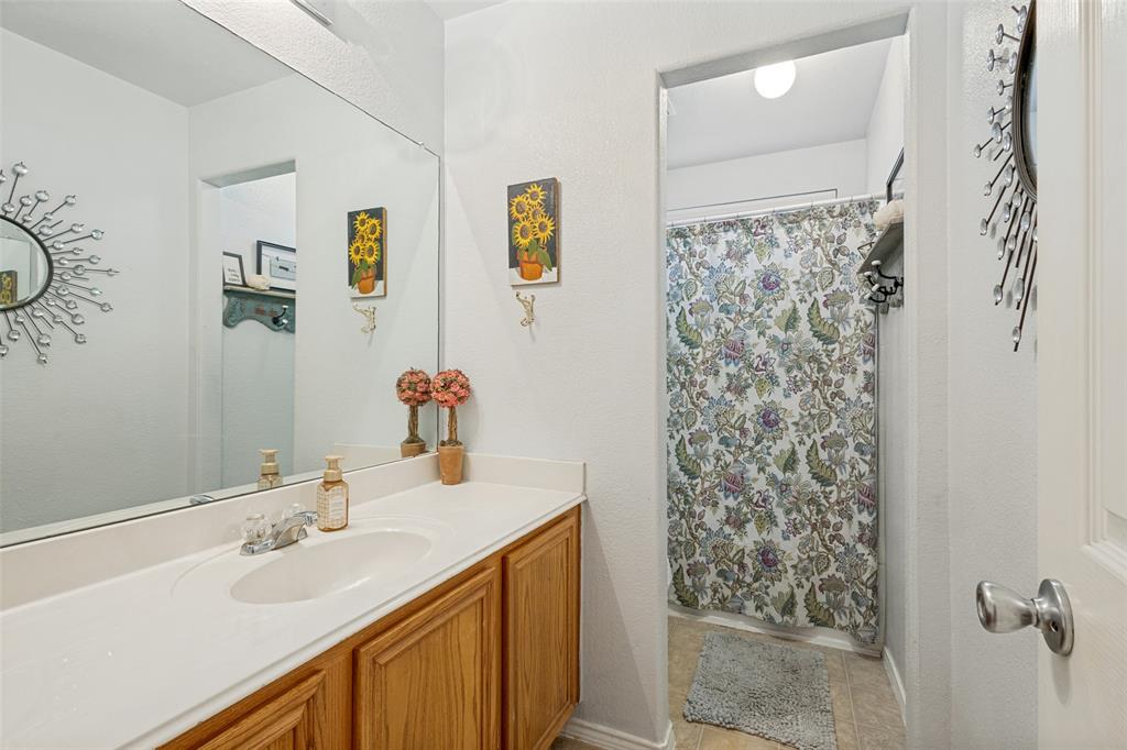 White vanity with a built-in sink, chrome faucet, and wood-finish cabinetry