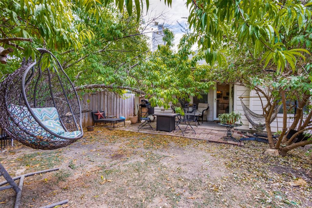 Expansive backyard featuring a brick paver patio, a white wood-paneled exterior, and mature trees