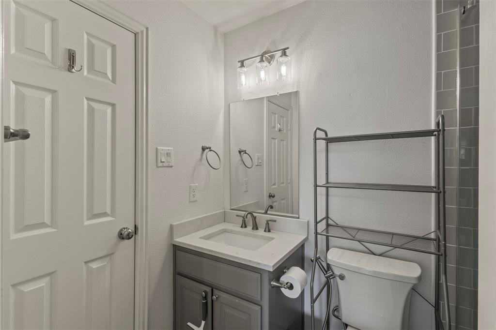 Vanity with integrated sink and chrome faucet, rectangular mirror, and three-light vanity bar