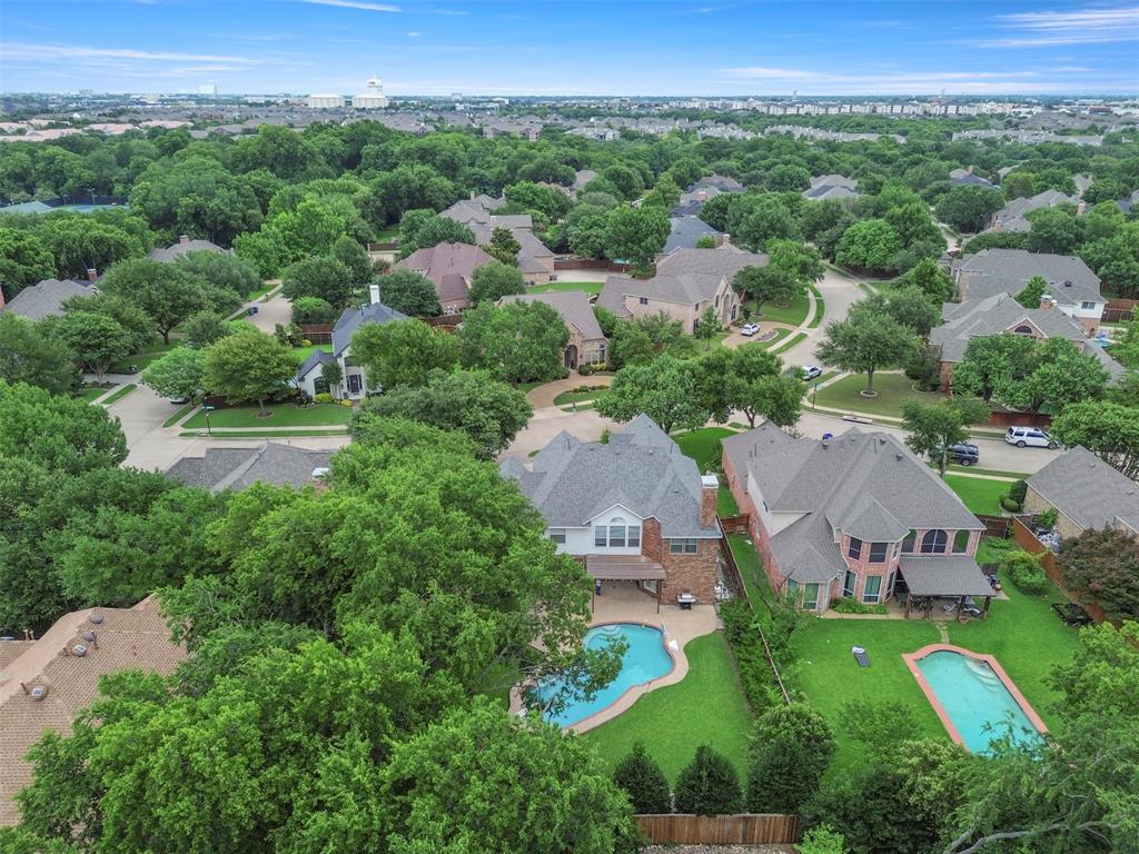 Expansive neighborhood featuring mature trees, multiple residential properties, and paved streets