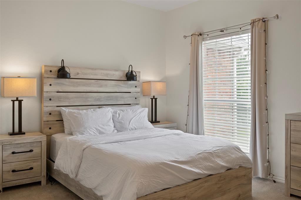 Serene primary bedroom featuring a wood-finish platform bed with horizontal slat headboard, wood-finish nightstands with drawer storage, paired table lamps with dark metal bases, and hardwood flooring