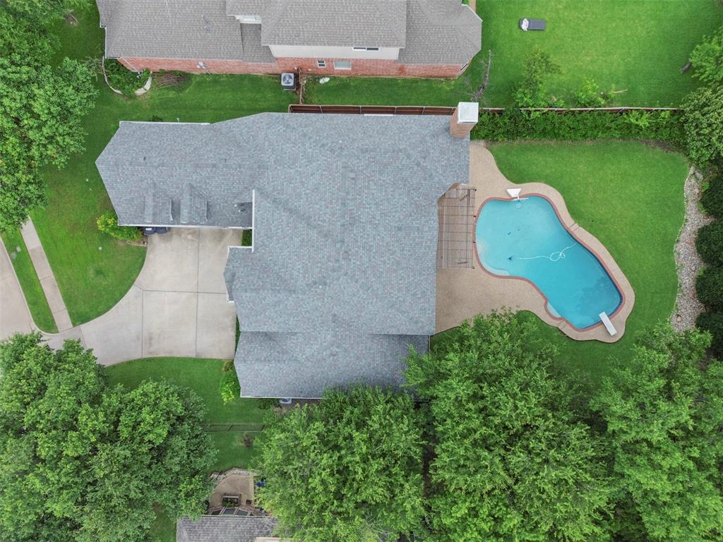 Expansive backyard with a freeform swimming pool, diving board, and surrounding concrete patio