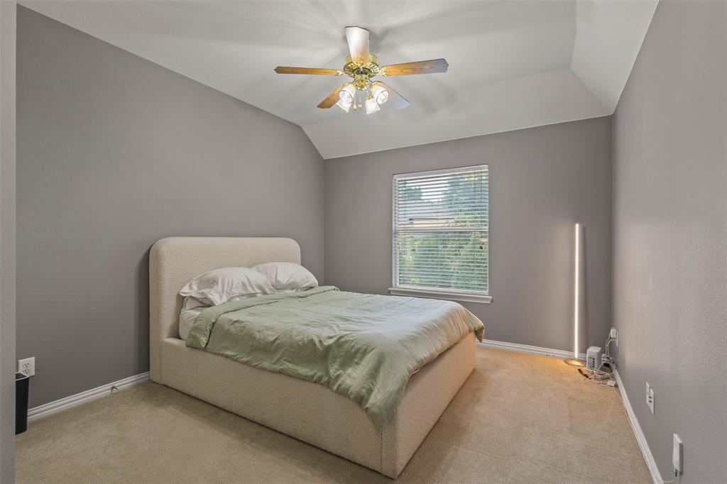Carpeted room featuring a window with blinds, ceiling fan with lighting, and vaulted ceiling