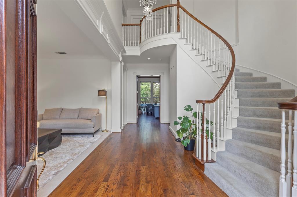 Wood-finish flooring with a curved staircase featuring carpeted treads, white balusters, and a rich wood handrail
