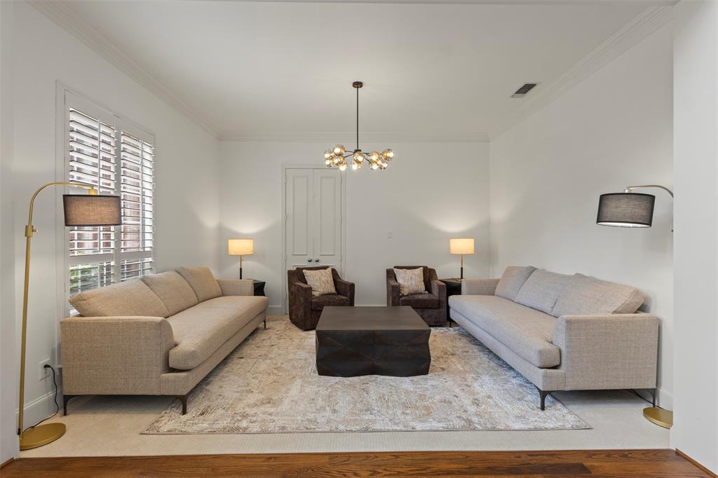Bright interior with crown molding, wood-finish flooring, plantation shutters, and a modern chandelier