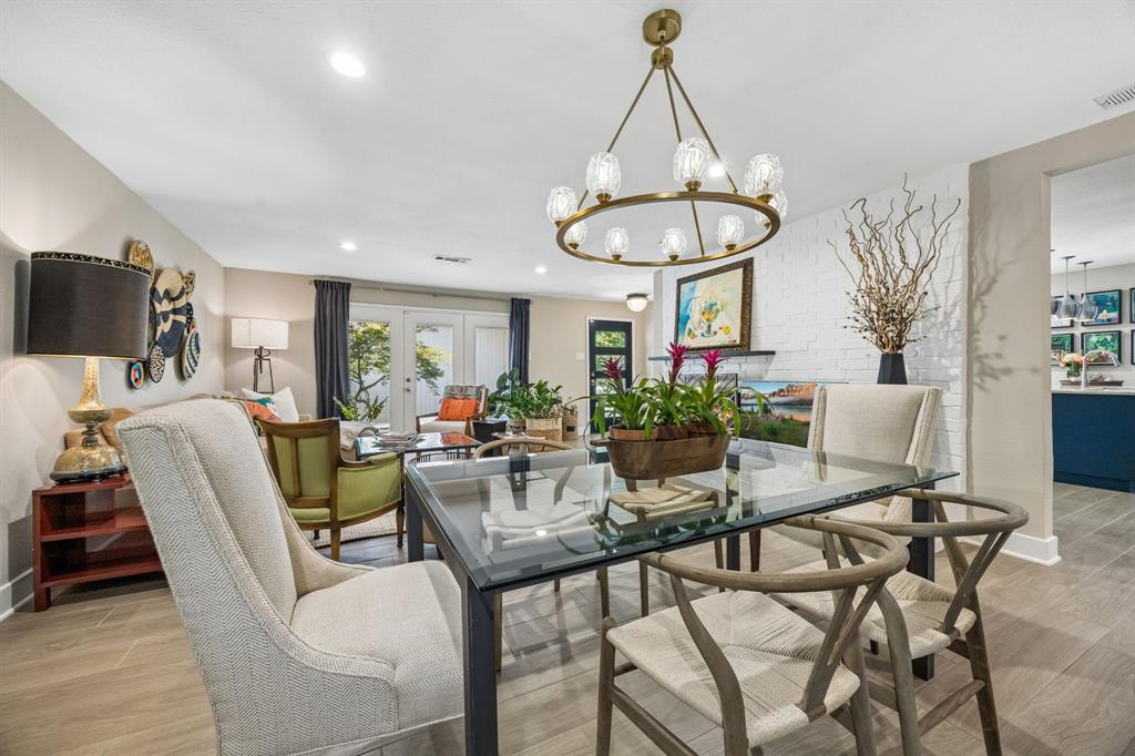Open-concept living space tile flooring, a contemporary chandelier, white brick accent wall, and double French doors