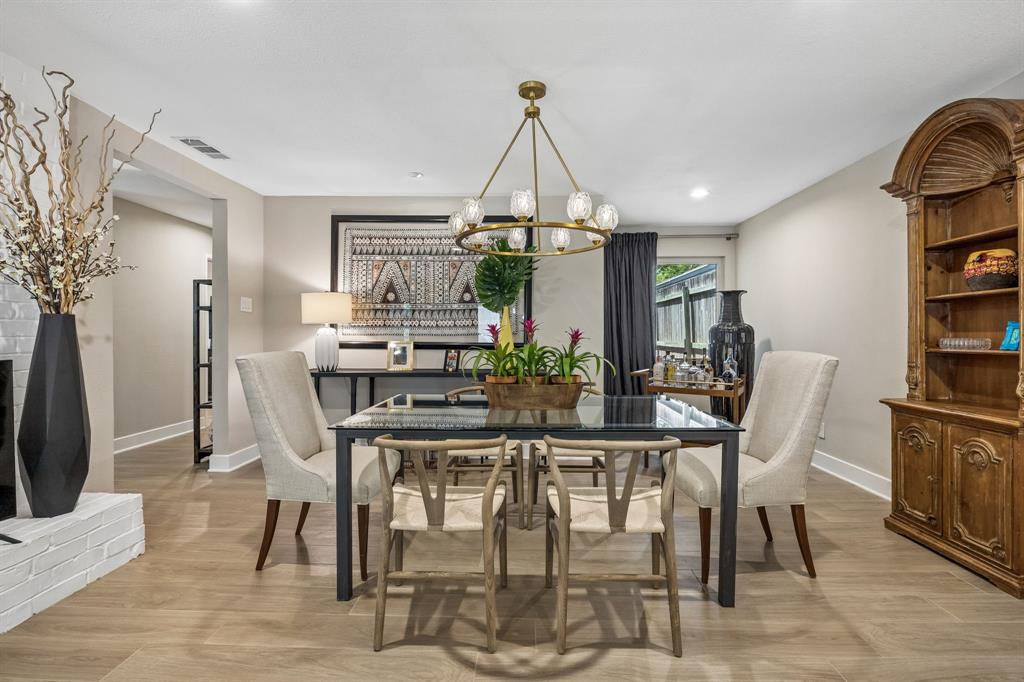 Dining area featuring tile  flooring, a contemporary chandelier, recessed lighting, and a white brick fireplace surround