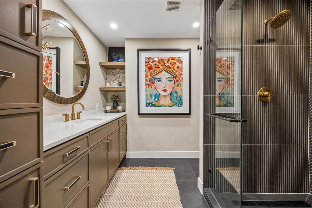 Built-in vanity with a white quartz countertop and gold-finish fixtures
