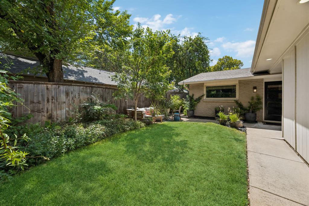 Expansive lawn with mature trees and a wood privacy fence