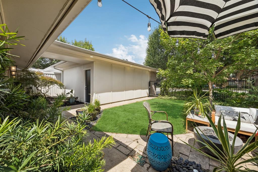 Private patio with stone pavers, bordered by a manicured lawn and mature landscaping