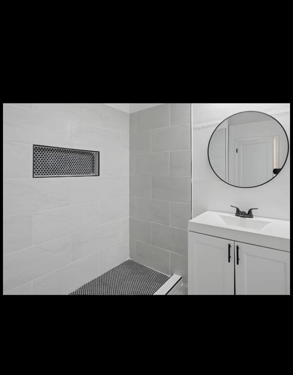 White tiled shower with a black honeycomb tile floor