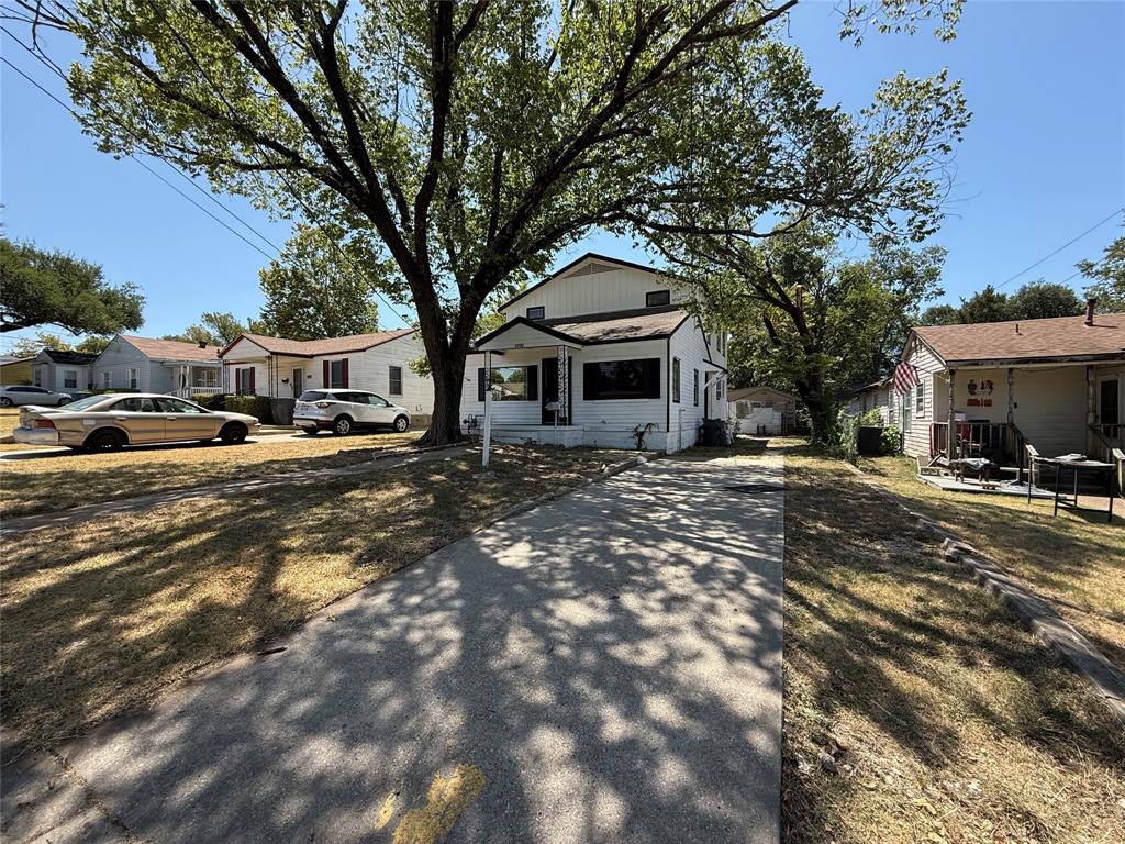 White exterior with black trim, covered porch entry, and mature trees providing natural shade