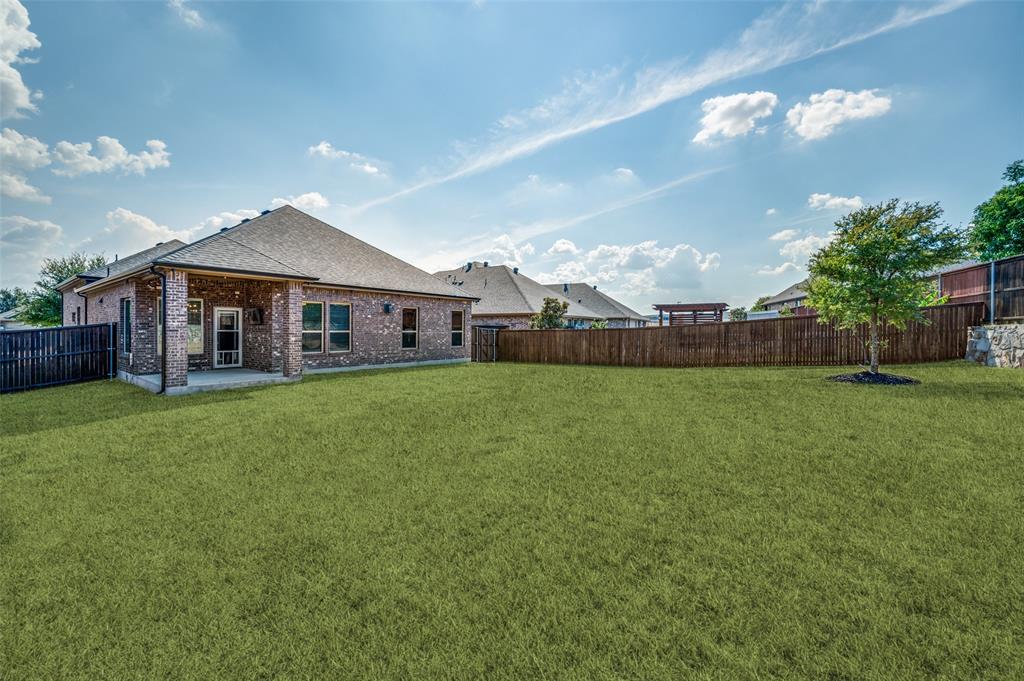 Expansive green lawn, a covered patio, and brick exterior