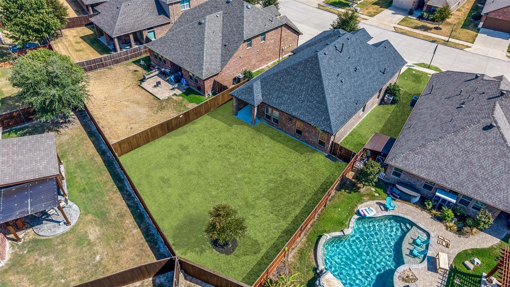 Expansive fenced backyard featuring a manicured lawn and a single ornamental tree