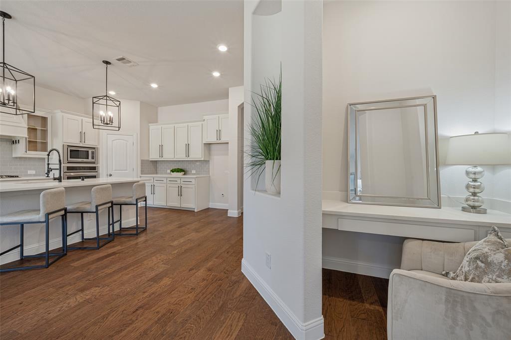Expansive wood-finish flooring, white shaker-style cabinetry, and recessed lighting